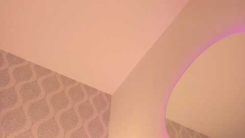 A video of an architectural detail featuring a curved, light pink wall with a subtle wavy pattern. The adjacent wall has a textured, light brown wallpaper with an elegant, wavy design. The image captures a warm, retro aesthetic.
