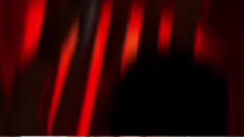 A blurred, abstract video featuring vertical, glowing red and orange lights against a dark background, creating a dynamic, almost mystical atmosphere. The image lacks distinct details or identifiable objects.