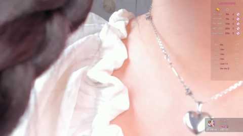 A video depicting a close-up of a man's dark-skinned face kissing a woman's fair-skinned neck, adorned with a delicate silver necklace. The background is blurred.