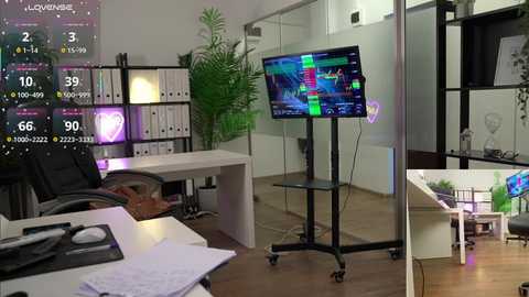 Video of a modern office with a large TV displaying sports on a stand, a white desk, bookshelves, and potted plants.