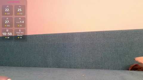 A video of a beige wall with a textured blue-green fabric couch, featuring a digital thermometer overlay showing 27 degrees Celsius and 10.5% humidity.