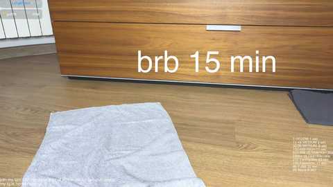 A video showing a wooden dresser with a 15-minute timer placed on a light wooden floor, featuring a white cloth and a black mat.