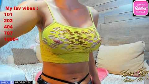 Video of a woman in a yellow, cut-out crop top revealing her breasts, standing in a bedroom with wooden walls and bedding. Text overlays indicate 1010+ views and 400+ votes.