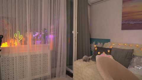 Video of a cozy, softly lit bedroom with a plush white bed, colorful string lights, sheer curtains, and a white lattice screen.
