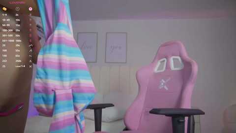 Video of a pastel-striped hoodie hanging on a pink gaming chair in a white room with minimalist decor.