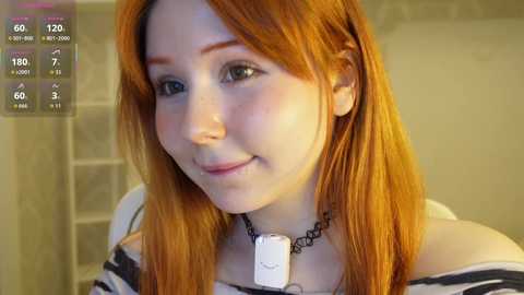 Video of a fair-skinned woman with long, straight red hair, wearing a black choker and a striped shirt. Background includes a blurred bathroom with a glass shower door.