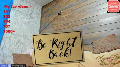 Video of a bedroom with a beige \"Be Right Back\" sign hanging on a wooden wall. Text overlays show social media numbers, \"Noia Noia\" watermark, and \"Krees Keen\" logo.