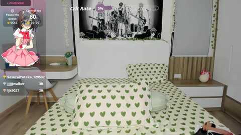 Video of a neatly made bed with green heart-patterned bedding in a modern, white-walled room. A framed black-and-white historical photo hangs above, and a desk with a laptop is visible in the left corner.