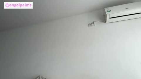 A video of a simple, minimalist room with a white wall and an air conditioner mounted high on the right. The image has a clean, modern aesthetic.
