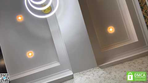 Video of a modern ceiling with three circular recessed lights and a bright white circular chandelier, set against white walls and a marble floor.