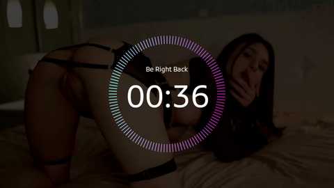Video of a woman in black lingerie, bent over a bed, with the text \"00:36\" and a musical note overlay.