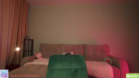 Video of a dimly lit, cozy bedroom with beige walls and plush furniture, including a green blanket on a bed with a stuffed Hello Kitty plush, a small bookshelf, and a red lamp.