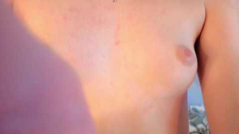 Media: Video of a fair-skinned, topless man with small, perky breasts and light pink nipples, captured from the waist up, with a blurred, indistinct background.