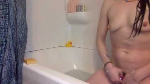 A video of a nude woman with wet, dark hair, standing in a white bathtub, holding a yellow rubber duck, in a bathroom with a blue-patterned shower curtain.