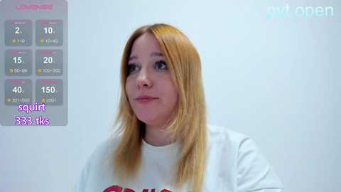 Video of a light-skinned, blonde woman with straight hair, wearing a white t-shirt, in a plain white background. A digital overlay displays heart rate and other metrics on the left.