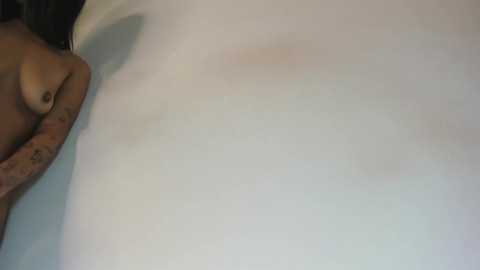 A video of a nude woman with medium-sized breasts, light skin tone, lying on her back, partially visible in the frame.