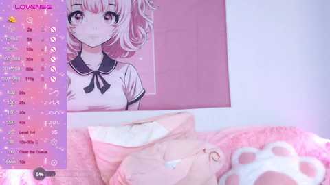 A soft-focus, pastel-colored video of a young woman with pink hair, wearing a sailor-style school uniform, hangs on a wall. A plush cat pillow lies on a bed in the foreground.