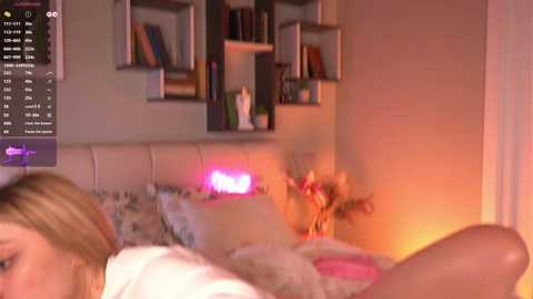 Video of a cozy bedroom with a white headboard, a pink neon sign reading \"LOVE,\" and a white fluffy blanket.