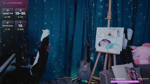 Video of a cozy room with a blue starry backdrop, featuring a black and white cat, a guitar, a painting easel with a colorful canvas, and a plush unicorn toy.