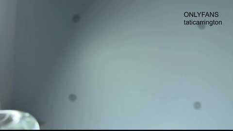 Video of a blurred, dimly lit room with two small, dark objects on a white surface. Text in the top right corner reads, \"ONLYFANS taicaringlot,\" suggesting adult content.