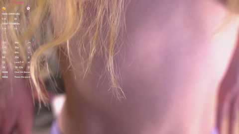 Video of a close-up of a woman's back with light blonde hair, showing a pinkish hue. Background shows a live stream interface with various chat messages.
