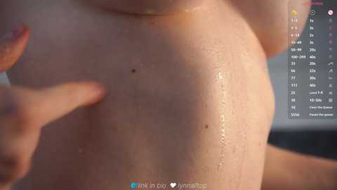 Video of a wet, nude woman with fair skin, showing her breasts, nipples, and wet hair. Background is blurred. Water droplets on skin. Social media handle visible.