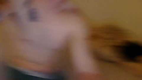 A blurred, motion-blurred video of a shirtless man with fair skin and a tattoo on his left arm, wearing dark pants, possibly running or moving quickly. The background is indistinct.