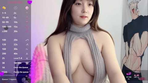 Video of a young East Asian woman with long black hair, fair skin, and medium-sized breasts, wearing a revealing, grey, ribbed halter-neck top. Background features a pink, textured wall and a partially visible anime character poster.