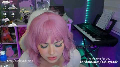 Video of a fair-skinned woman with pink hair, wearing a white veil, playing a black keyboard in a dimly lit room with colorful neon lights.