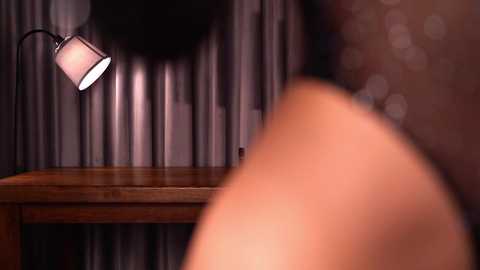 Video of a dimly lit room with a wooden table, a hanging lamp, and blurred figure in the background, creating a cozy, intimate atmosphere.