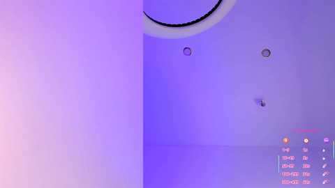 Video of a minimalist, purple-lit room with a large circular ceiling light, three ceiling-mounted lights, and a control panel displaying various settings.