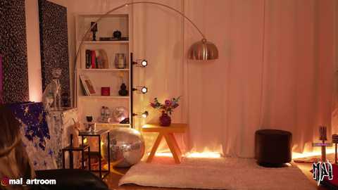 Video of a cozy, warmly lit room with beige curtains, a wooden table, a metallic lamp, and vibrant flowers.