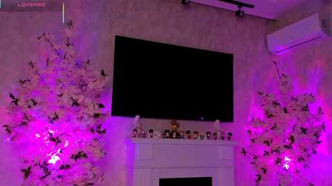 A video of a dimly lit room with a large flat-screen TV mounted on a beige wall, adorned with pink and purple LED lights, and a white fireplace adorned with miniature Christmas figurines.