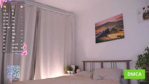 Video of a minimalist bedroom with beige curtains, a wooden bed, and a framed landscape painting on a white wall. The room has a modern, clean aesthetic.