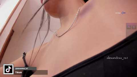 A close-up video of a woman's neck and shoulder, wearing a silver necklace, taken from a low angle, with a watermark and music note overlay.