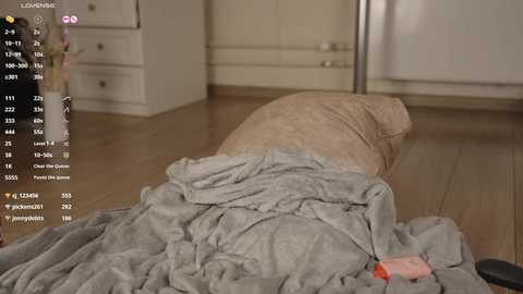 Video of a messy bedroom with a beige comforter, wooden floor, white dresser, and a partially visible white door, featuring a digital screen overlay with user data.