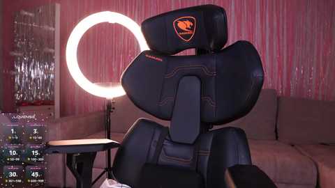 A video of a black gaming chair with a lit ring light, surrounded by pink curtain walls, featuring a \"Logitech\" logo.