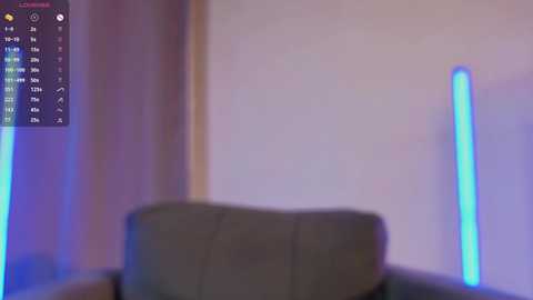 A video of a dimly lit room with two blue LED lights casting a soft glow on a grey couch. The background is blurred, creating an abstract, dreamy ambiance.