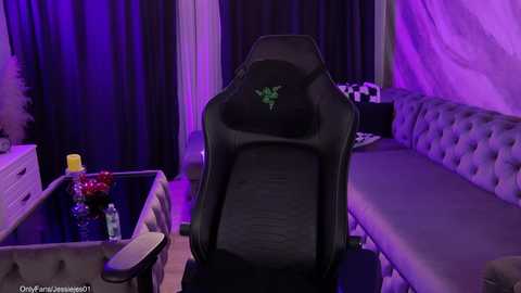 Video of a luxurious, purple-lit gaming room with a black gaming chair, plush sofa, and a desk adorned with decorative items.