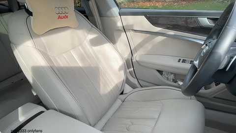 Video of a luxurious, cream-colored Audi car interior featuring plush leather seats, an Audi emblem, a spacious dashboard, and a sunlit window view.