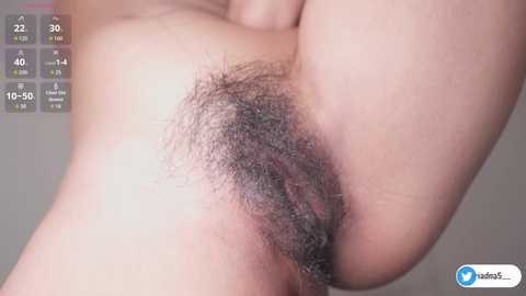 Close-up video of a female's vulva with dark pubic hair, displaying natural skin texture and color. Background includes a video recording screen with temperature, humidity, and air quality readings.