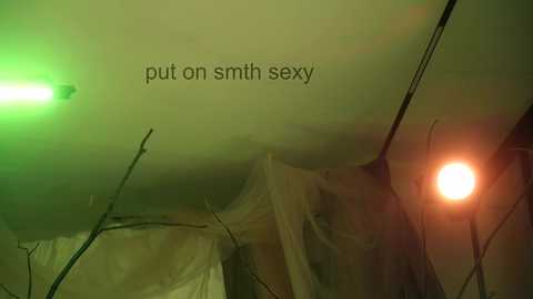 Video of a dimly lit, cluttered room with a green and orange glow, showing a beige ceiling, a white tent-like structure, and a small, dim light. Text on image reads: \"put on smith sexy.\