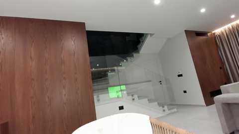 Video of a modern, minimalist interior with a wooden wall, glass railing, white stairs, and a beige couch, featuring a bright, spacious, contemporary design.