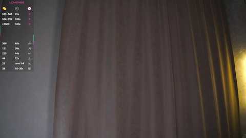 A dimly lit video of a room with a beige curtain partially drawn, revealing a window with a digital calendar displaying various dates and times.