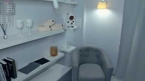 Video of a minimalist, modern office space with white walls, shelves, and a gray chair; features a white lamp, a decorative white dog, white ceramic mugs, and a silver desk organizer.