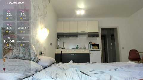 Video of a minimalist, modern bedroom with a loft bed, white wall mural, small kitchenette, and a wooden chair.