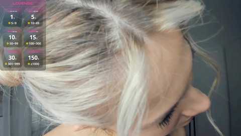 Video of a woman with platinum blonde hair styled in loose waves. Her face is partially visible, showing light makeup. A digital app overlay displays hair growth statistics.