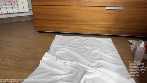 A video of a wooden-floored bedroom with a white towel on the floor, a wooden dresser, and a partially visible window with heart-shaped decals. Text in the image mentions cleaning and hygiene.