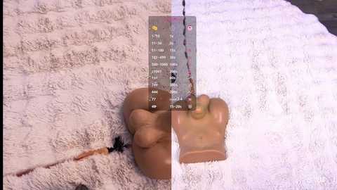 Video of a person's hand holding a syringe, with a needle inserted into a clear, cylindrical container filled with a beige liquid. The background is a white, textured towel.