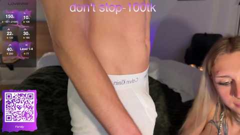 Video of a light-skinned, muscular man wearing Calvin Klein underwear, in a bedroom with a blonde woman partially visible, with a \"don't step 100k\" overlay.